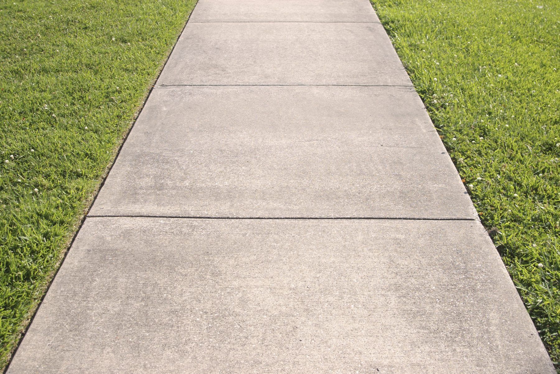 A man is spreading concrete on a sidewalk.