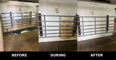 A person in a white hazmat suit and mask uses a sprayer to sanitize a cattle feeding trough inside a wooden barn.