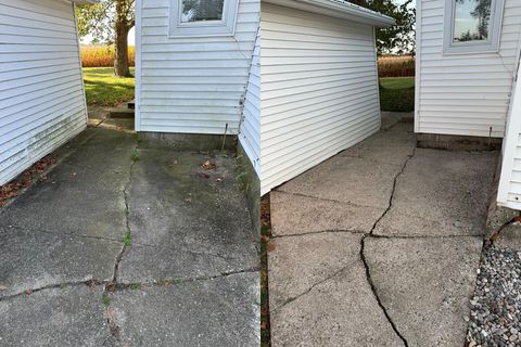 Cracked concrete walkway beside white-sided buildings and a small sloped ramp.