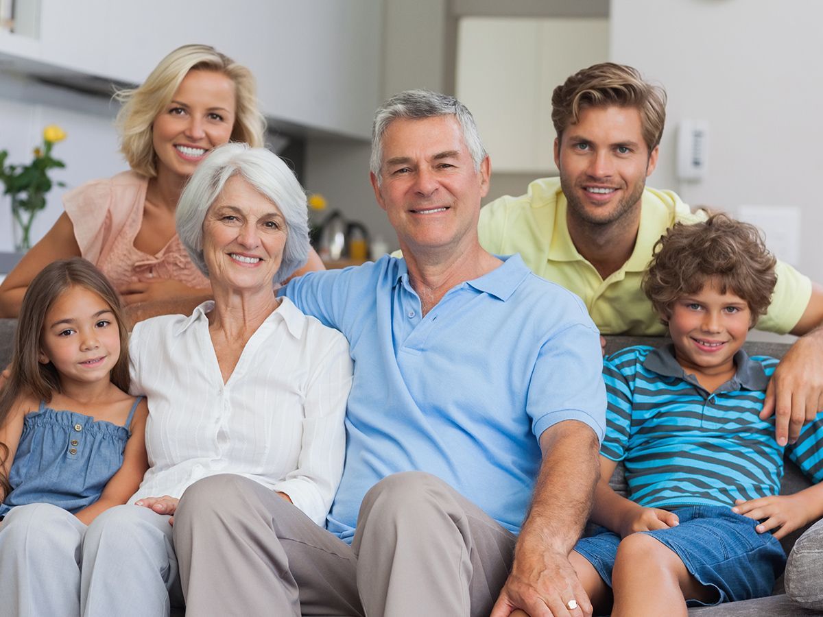 Family portrait: Three generations smiling together on a couch.