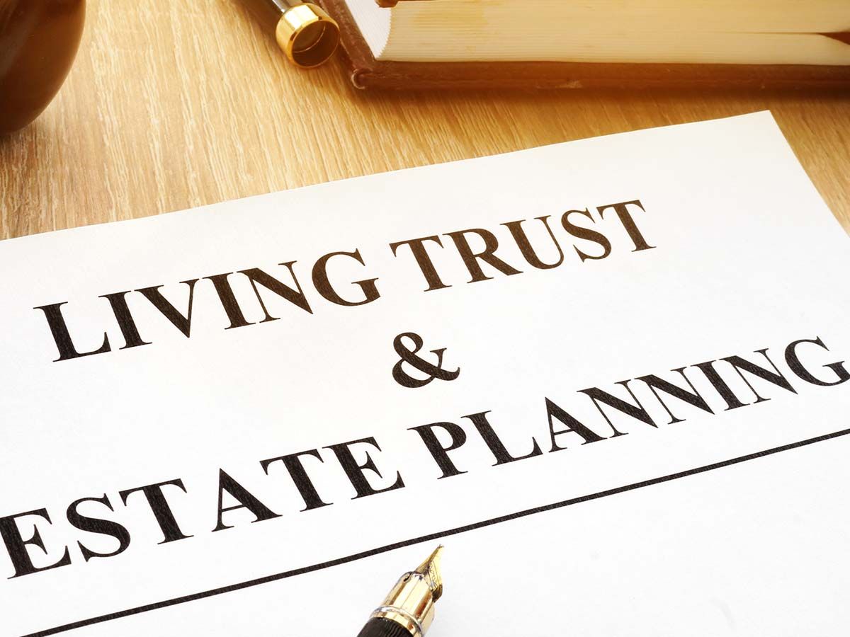 Living Trust & Estate Planning document on a wooden desk with a pen and book.