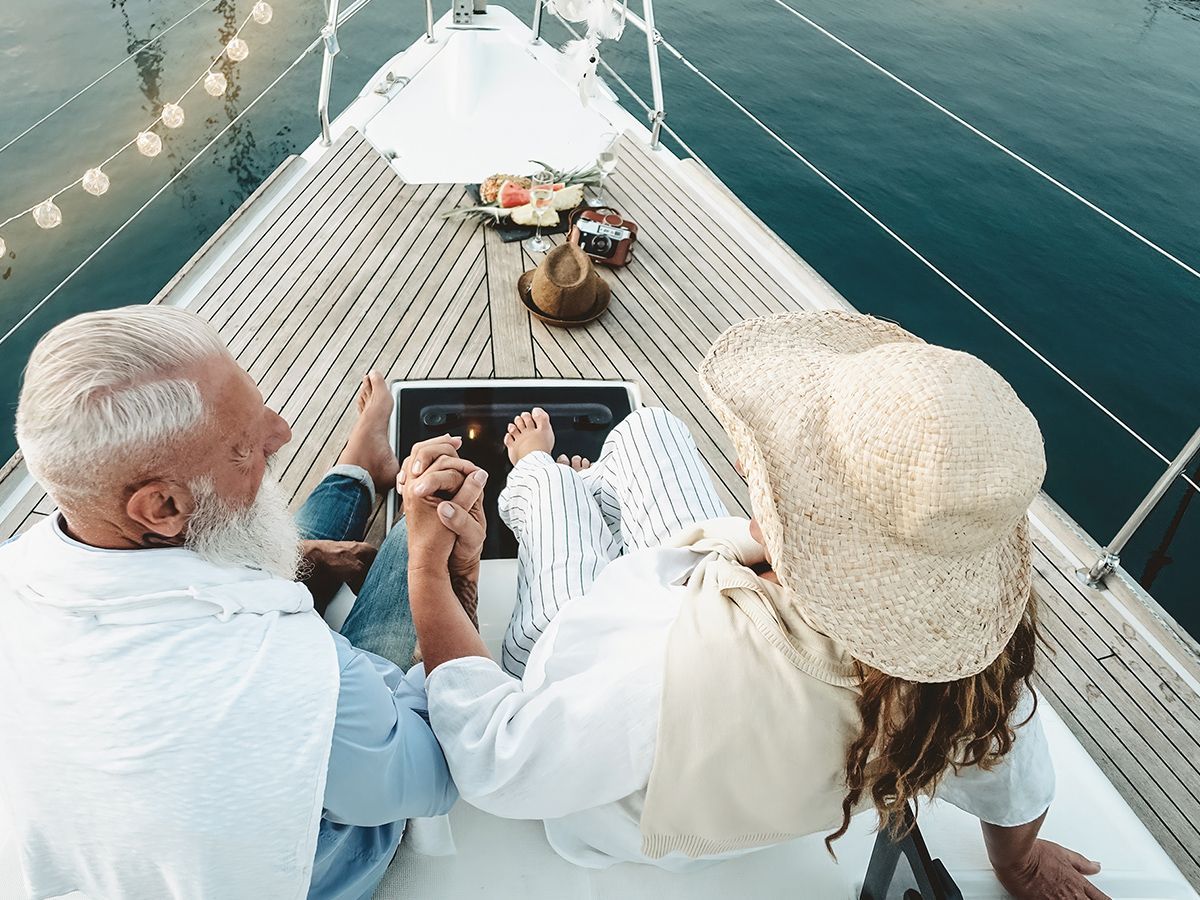 Couple holding hands on a sailboat deck, ocean view.