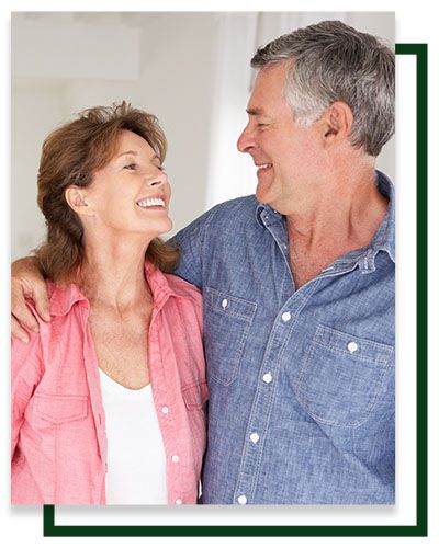 Smiling couple embracing, looking at each other. Man in blue shirt, woman in pink.