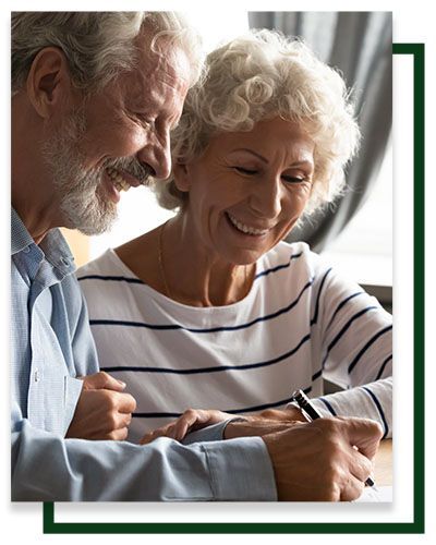 Smiling older couple writing together at a table.