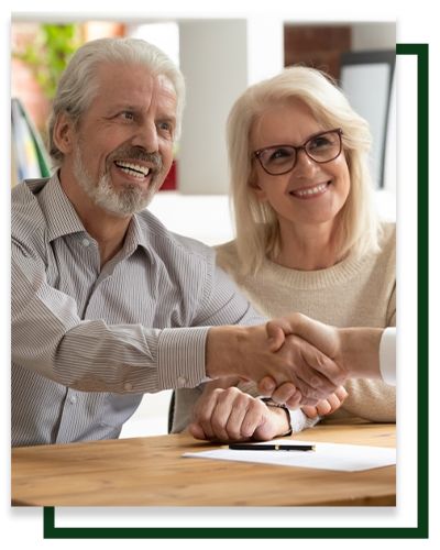 Couple shaking hands over a contract, smiling.