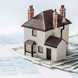 Miniature house model on money and tax forms.