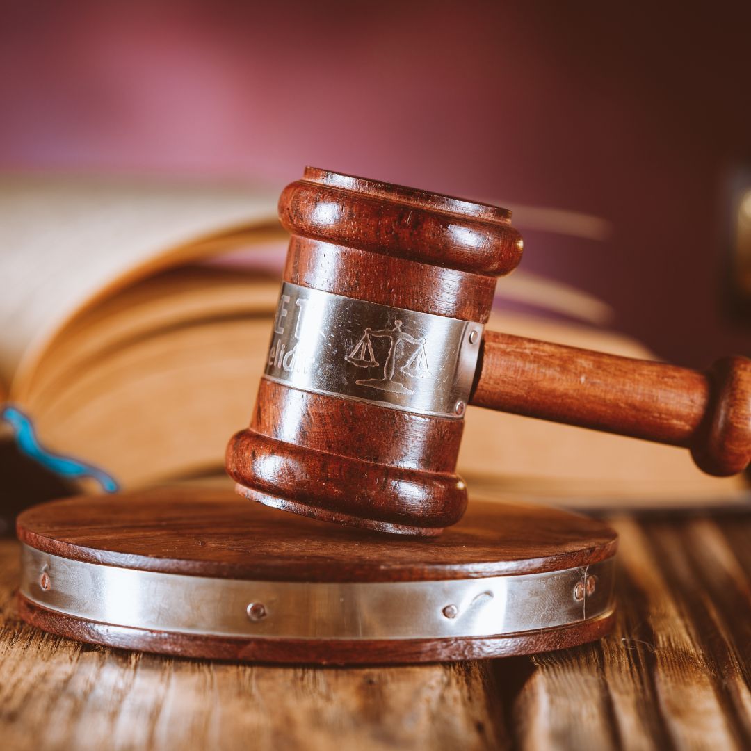 Wooden gavel on a sound block with an open book in the background.