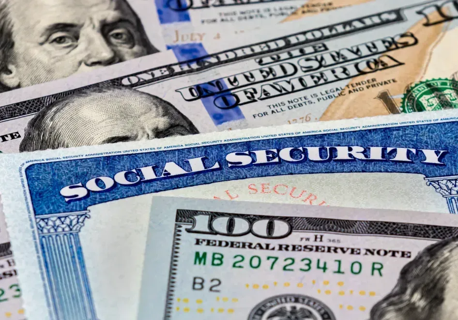 Social Security card with US $100 bills in the background.