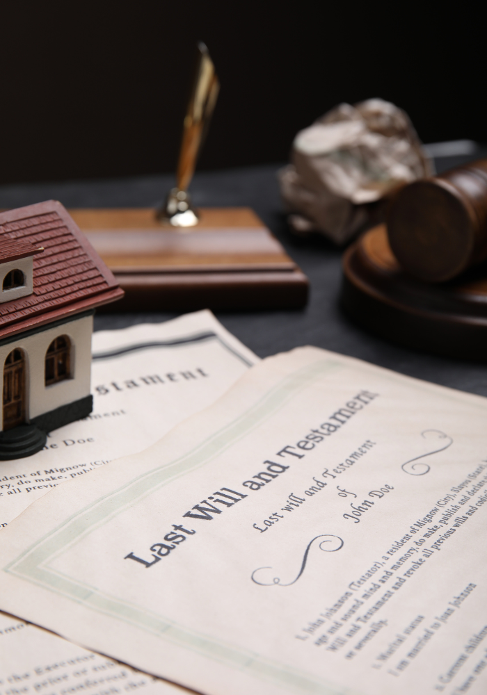Last Will and Testament document with a miniature house, pen, gavel, and rocks.
