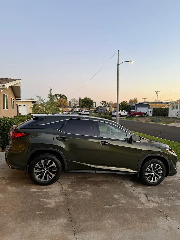 Dark green SUV parked on a concrete driveway at dusk in a residential neighborhood.