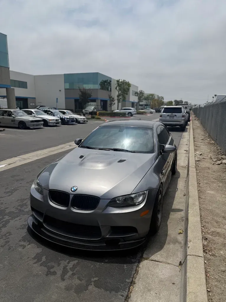 Gray BMW parked on a curbside street beside a warehouse parking lot