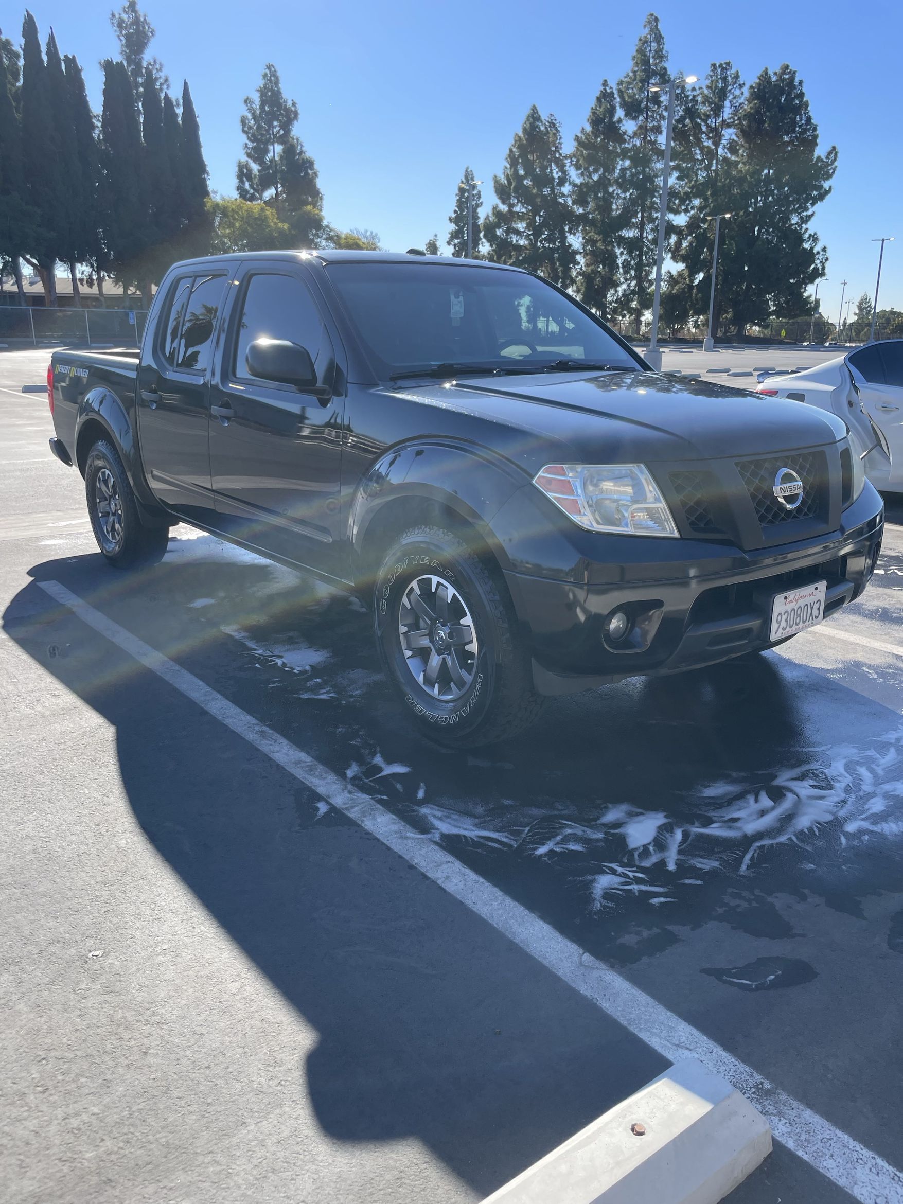 Dark gray pickup truck parked in a snowy lot on a sunny day