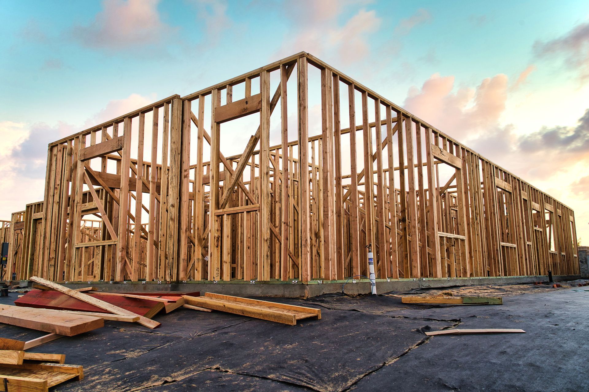 Wooden frame of a building under construction against a cloudy sky.