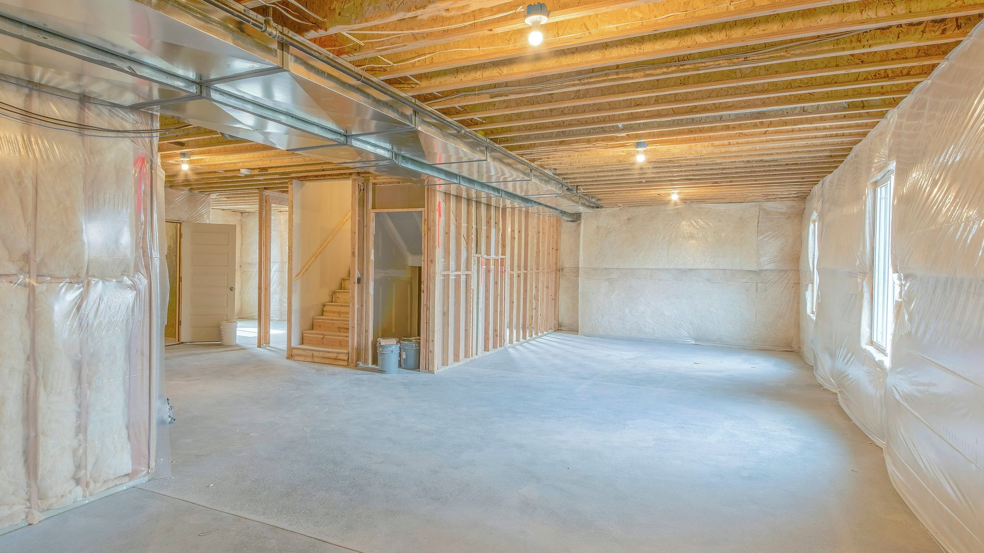 Unfinished basement with exposed framing, ductwork, insulation, and concrete floor.