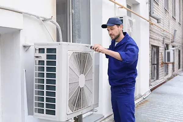 Male technician repairing air conditioner outdoors
