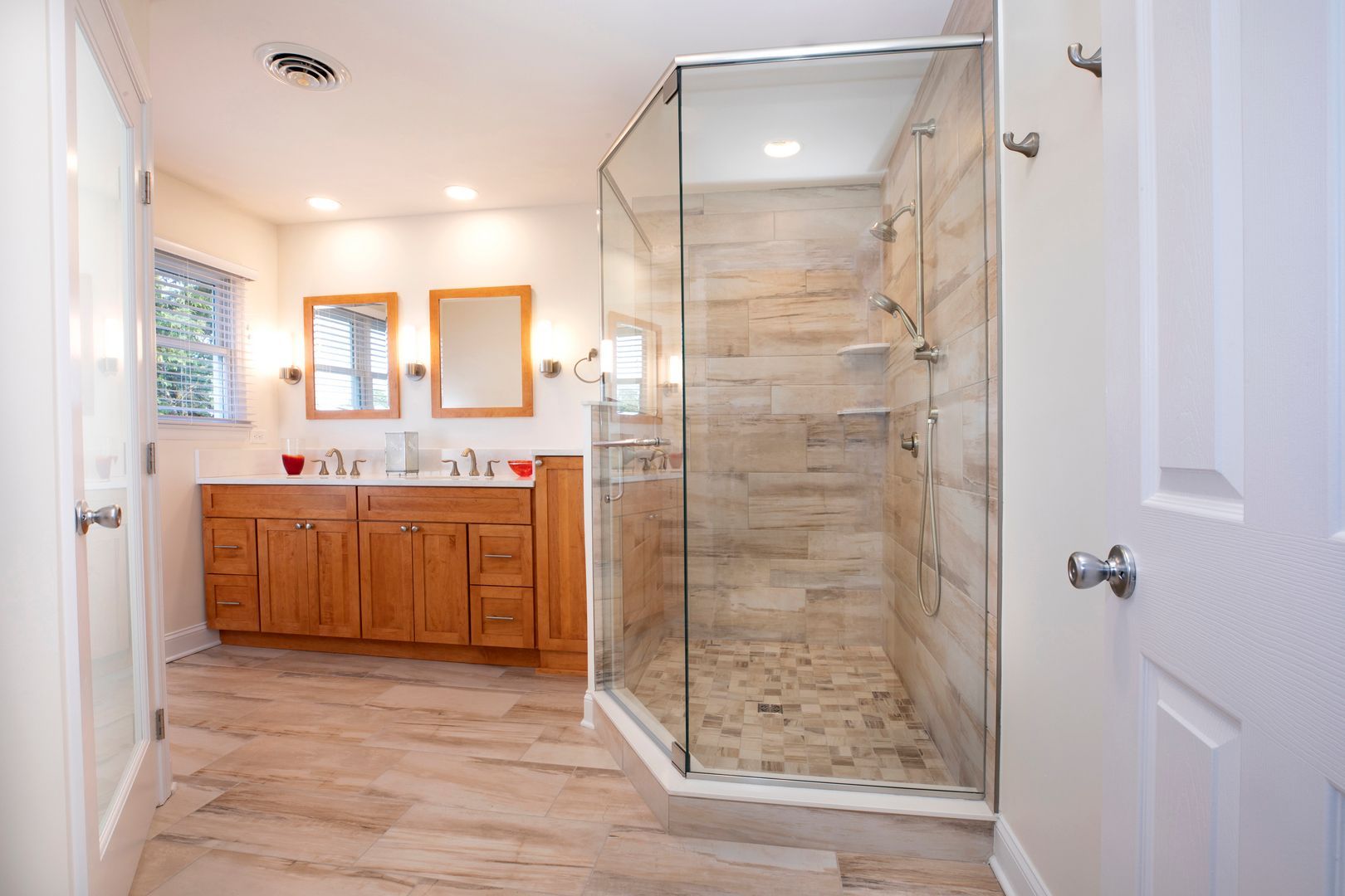 A bathroom with a walk in shower and two sinks.