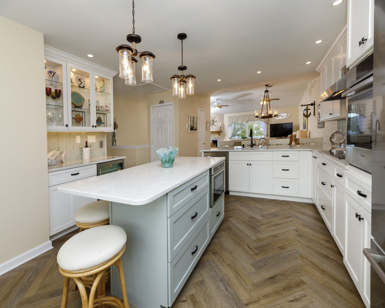 A kitchen with white cabinets , stainless steel appliances , and a large island.