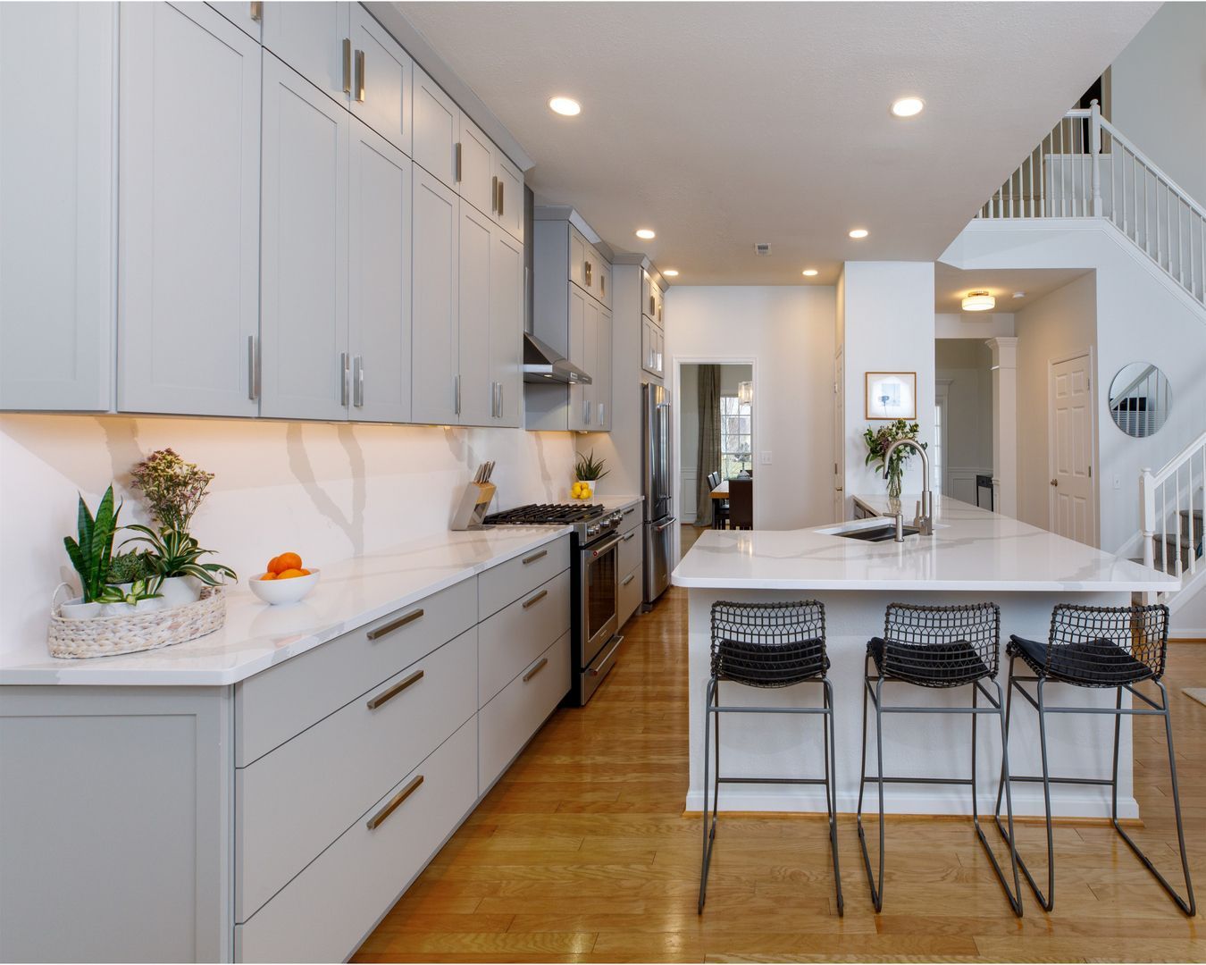 A kitchen with white cabinets , stainless steel appliances , and a large island.