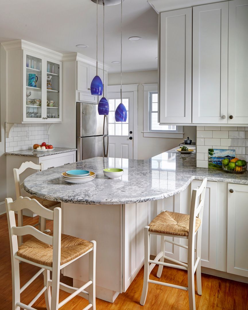 A kitchen with white cabinets and a marble counter top