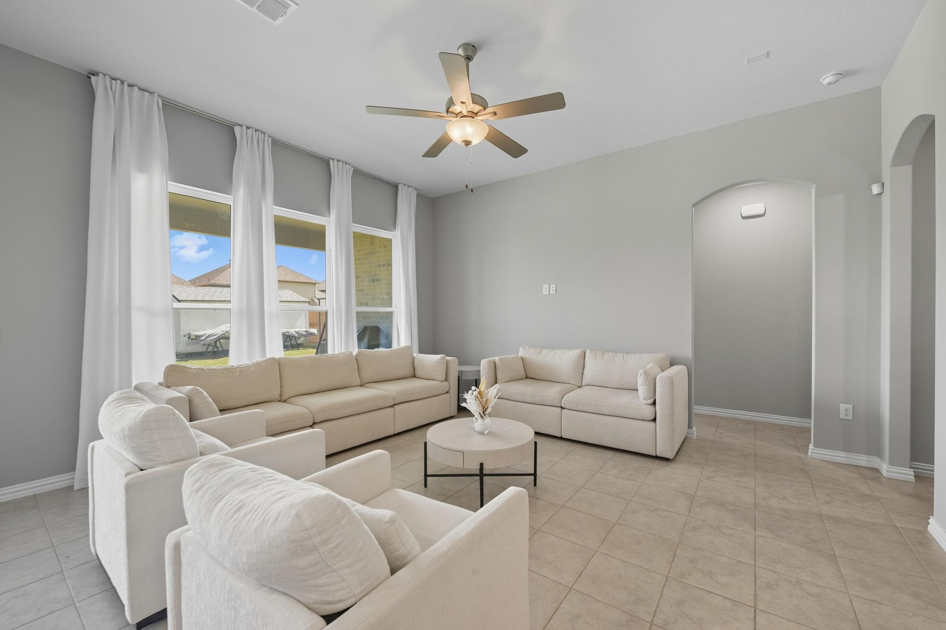 A living room with a couch , chairs , ottoman and a mirror