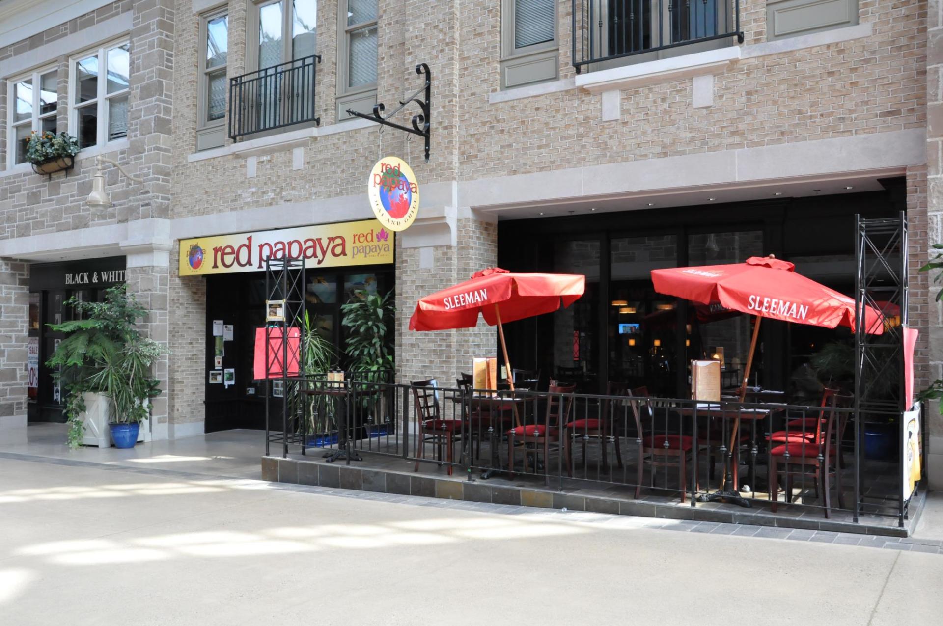 Exterior of Red Papaya restaurant with outdoor seating and red umbrellas.