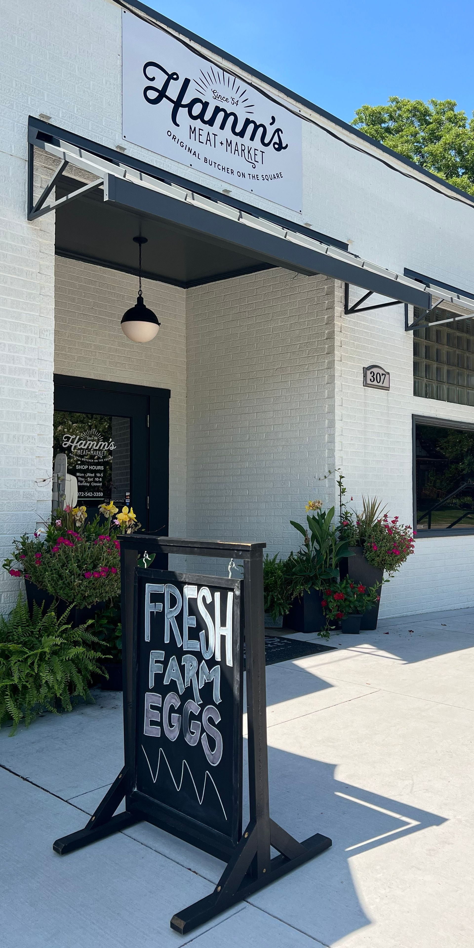A white building with a sign that says `` fresh farm eggs '' in front of it.