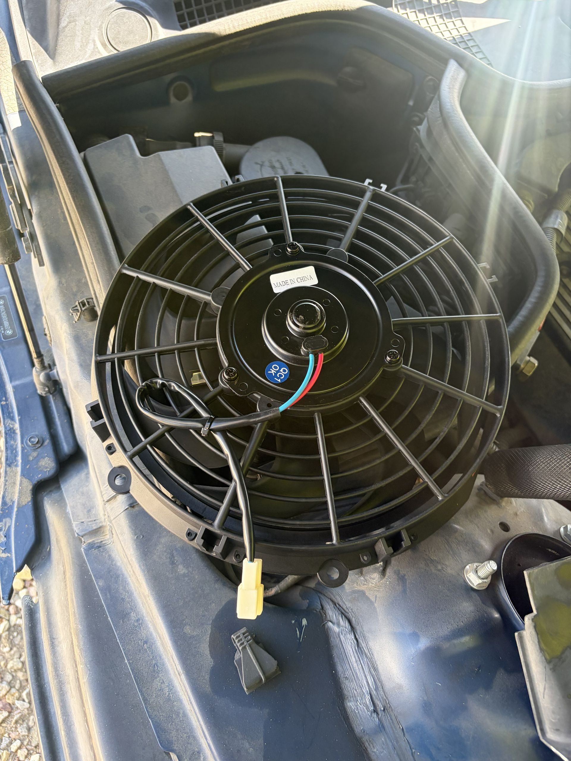 Open car dashboard with a large black cooling fan and exposed wiring inside.