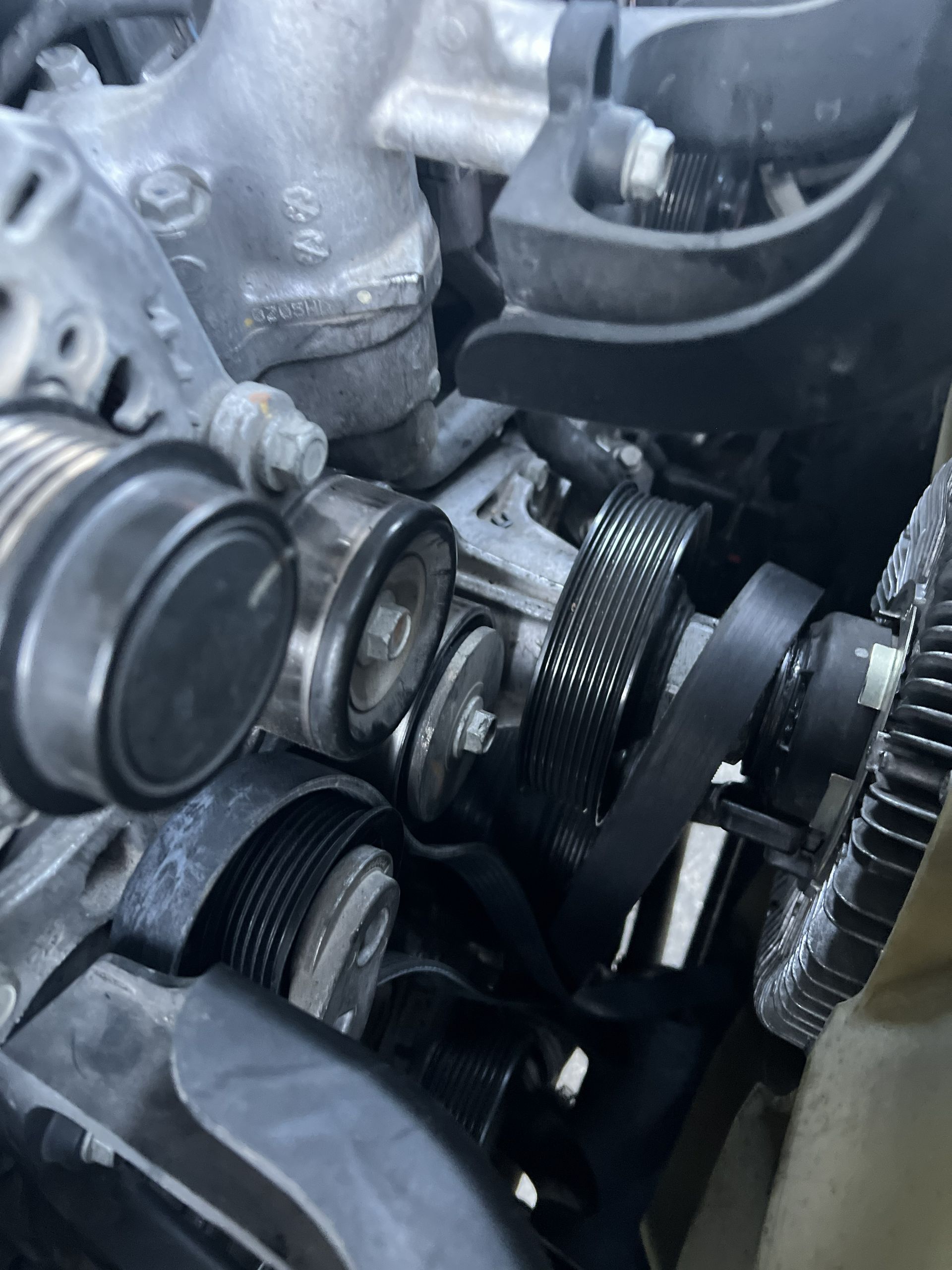 Close-up of an engine timing belt and pulleys inside a car engine compartment