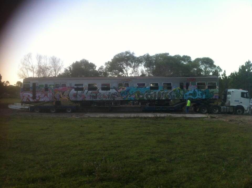 A train car with graffiti on it is being transported by a truck.