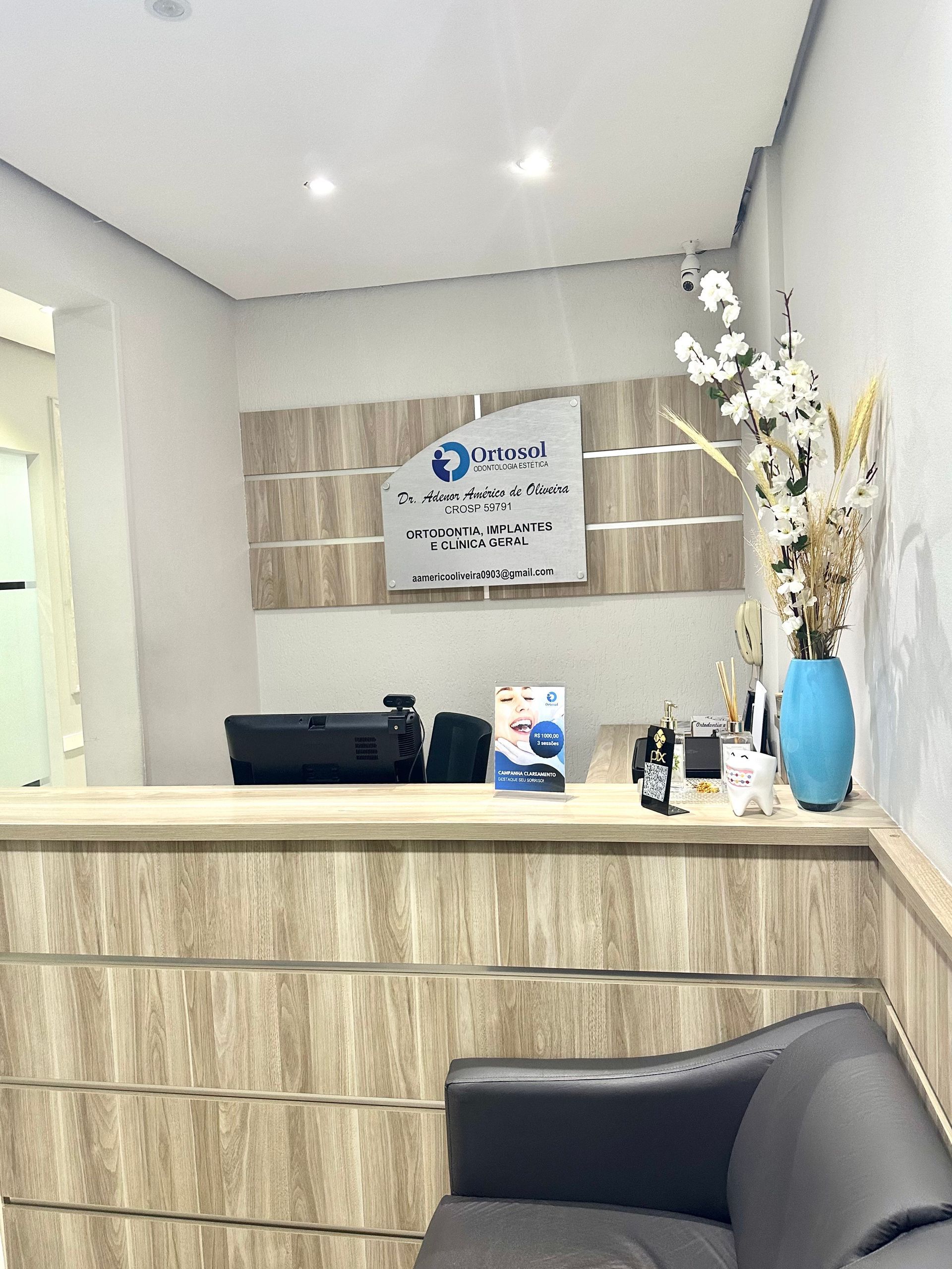 Balcão de recepção com logotipo, flores e um sofá preto.