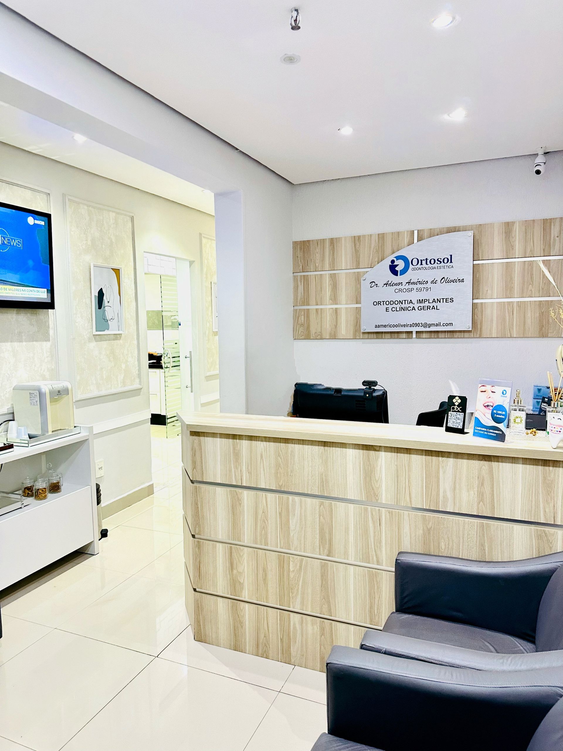 Área de recepção de um consultório médico com balcão de madeira e sala de espera.