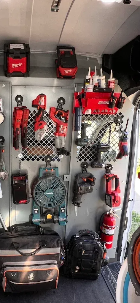 Tools neatly organized in a van, featuring power tools, a fan, and tool bags.