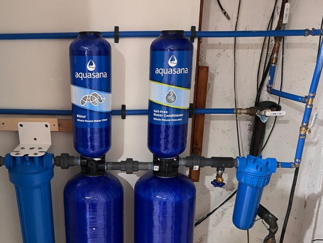 Blue water filtration system with Aquasana filters installed on a wall.