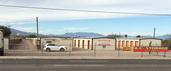 A white suv is parked in front of a storage facility.