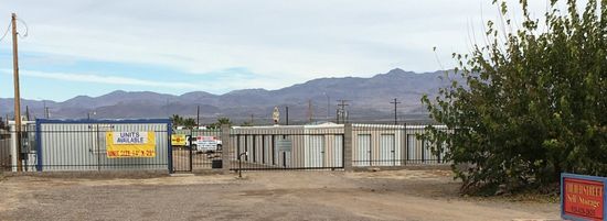 A fenced in area with mountains in the background and a sign on the side of the road.