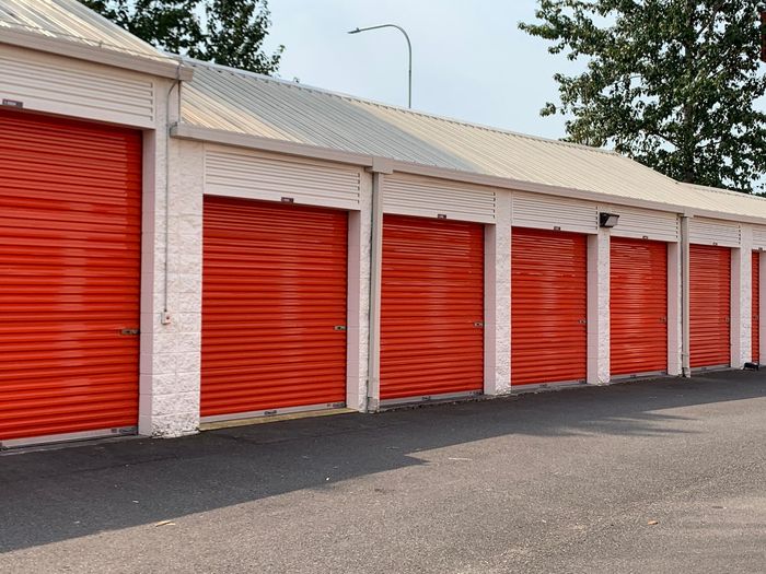 A row of red garage doors are lined up in a parking lot. A row of red garage doors are lined up in a parking lot.
