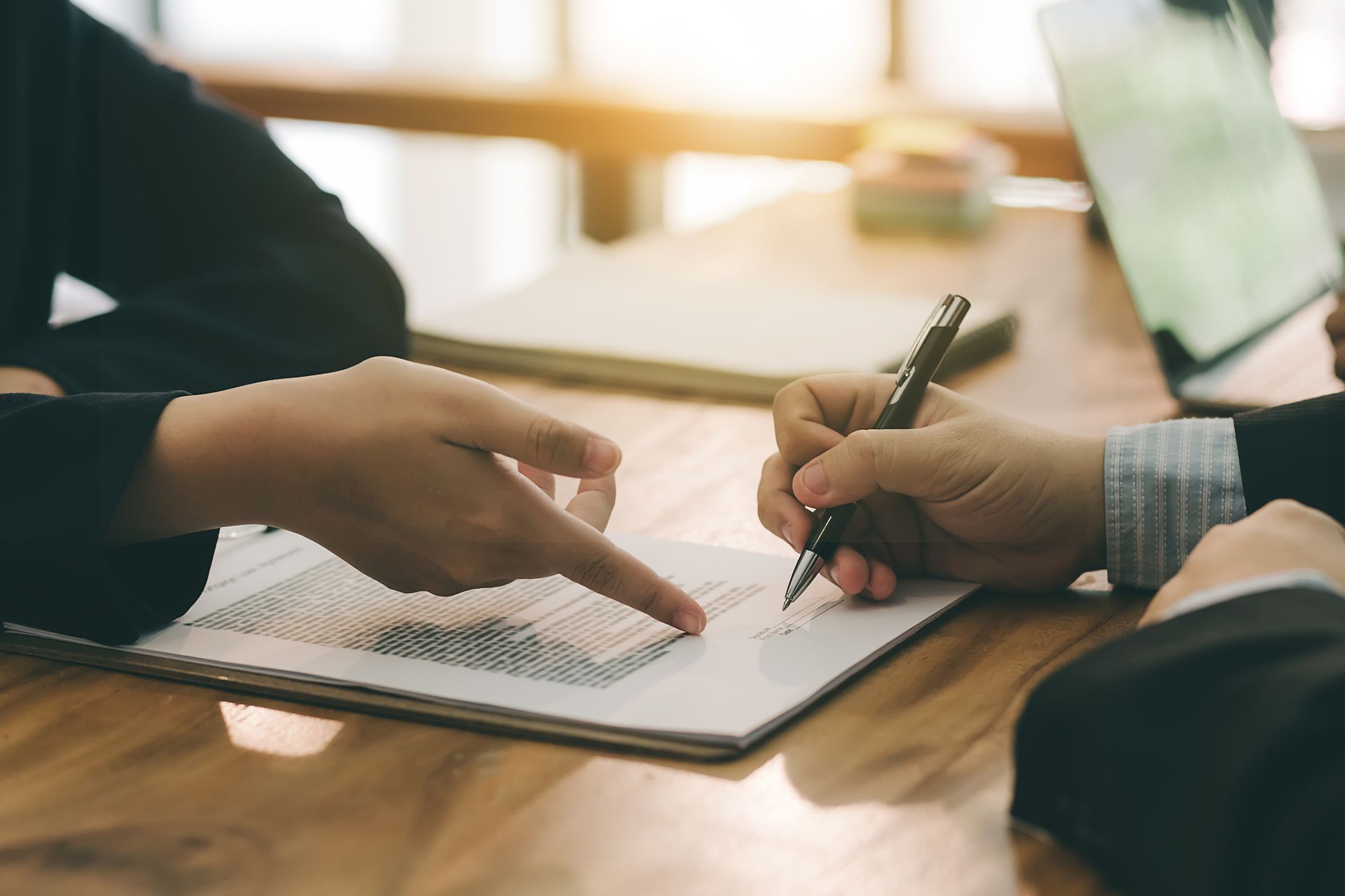 Two people are sitting at a table signing a document - Perth, WA - Allos Parakletos