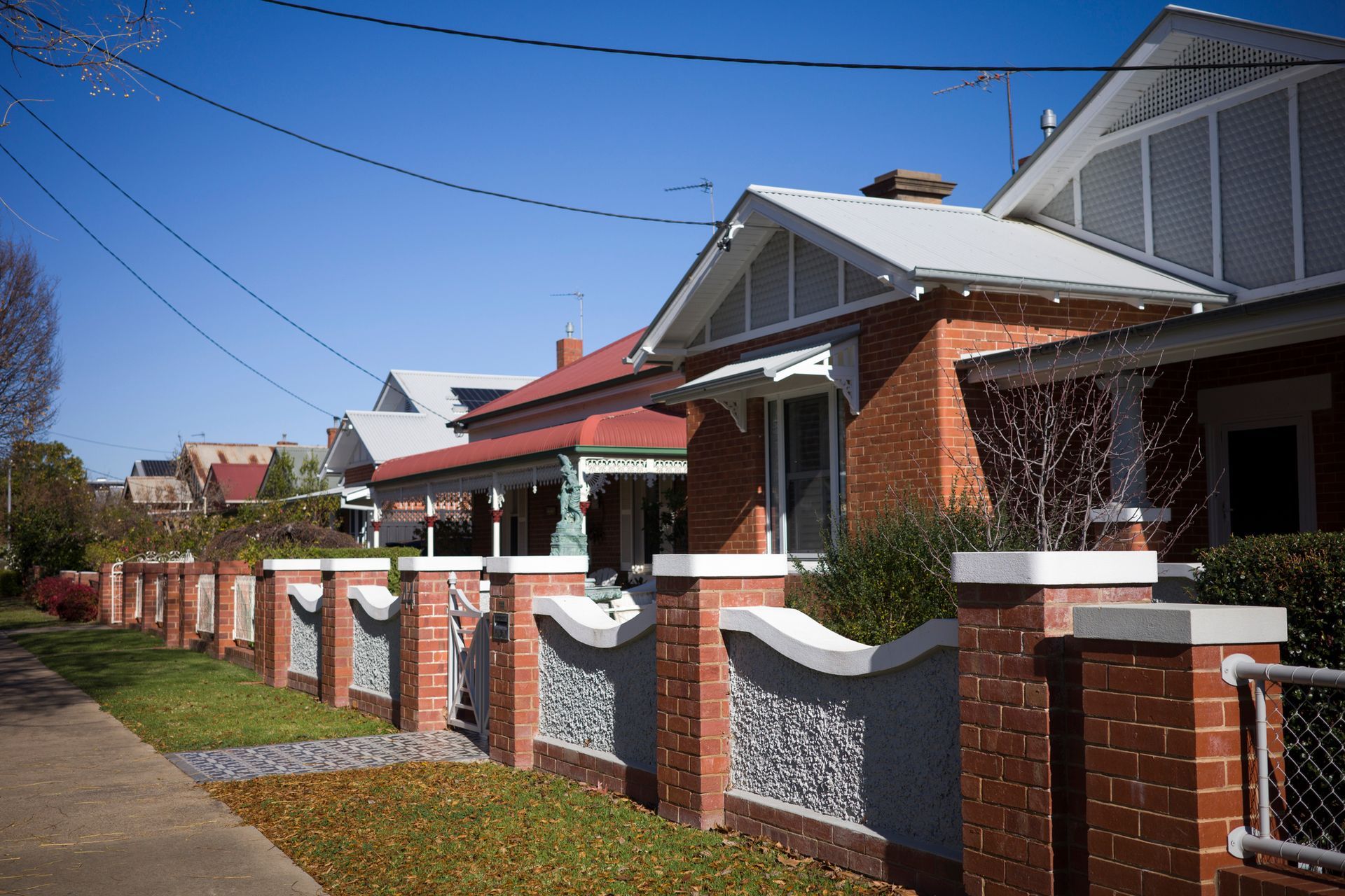 A row of houses with a brick fence in front of them - Perth, WA - Allos Parakletos