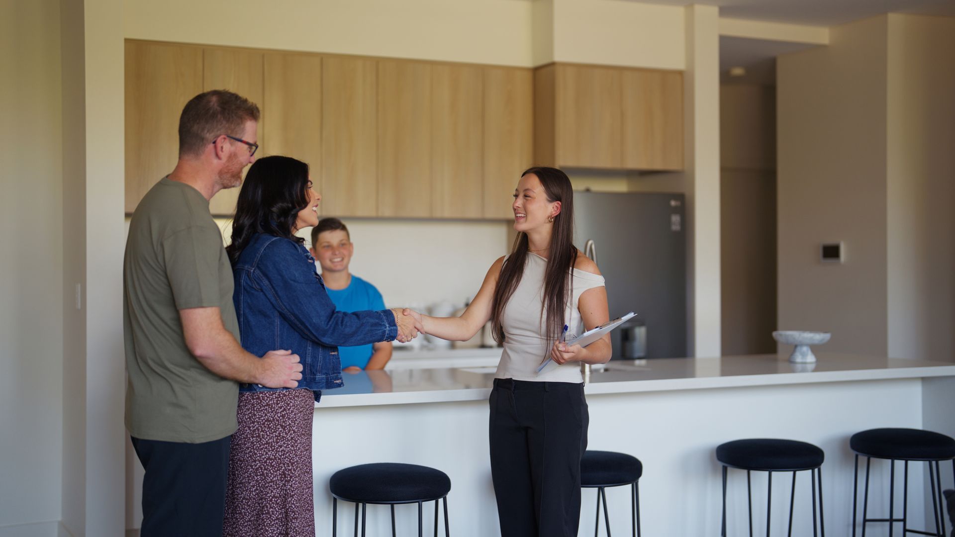 A woman is shaking hands with a man and woman in a kitchen - Perth, WA - Allos Parakletos