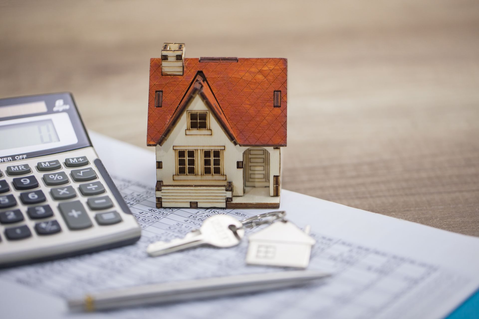 A model house, keys, and a calculator are on a table - Perth, WA - Allos Parakletos