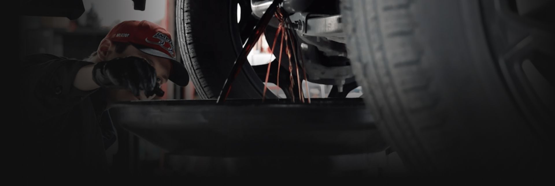 Person working on a vehicle, sparks flying from a grinding tool.  Low angle shot, dark setting. | Auto Medics of Missoula