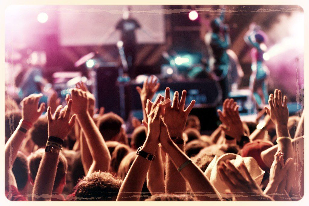 A crowd of people with their hands in the air at a concert