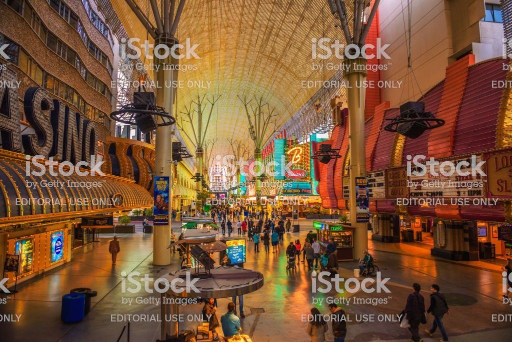 A crowd of people are walking down a busy street in a casino.