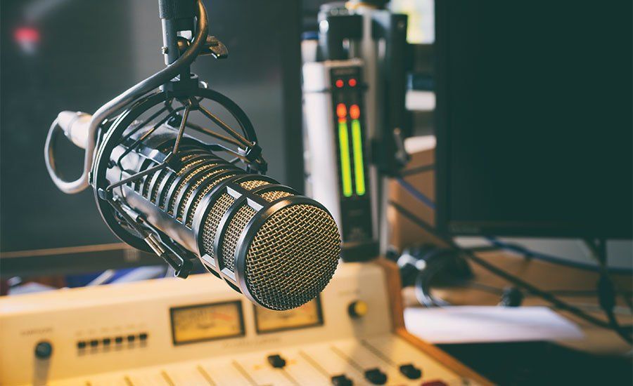 A microphone is sitting on top of a mixer in a radio studio.