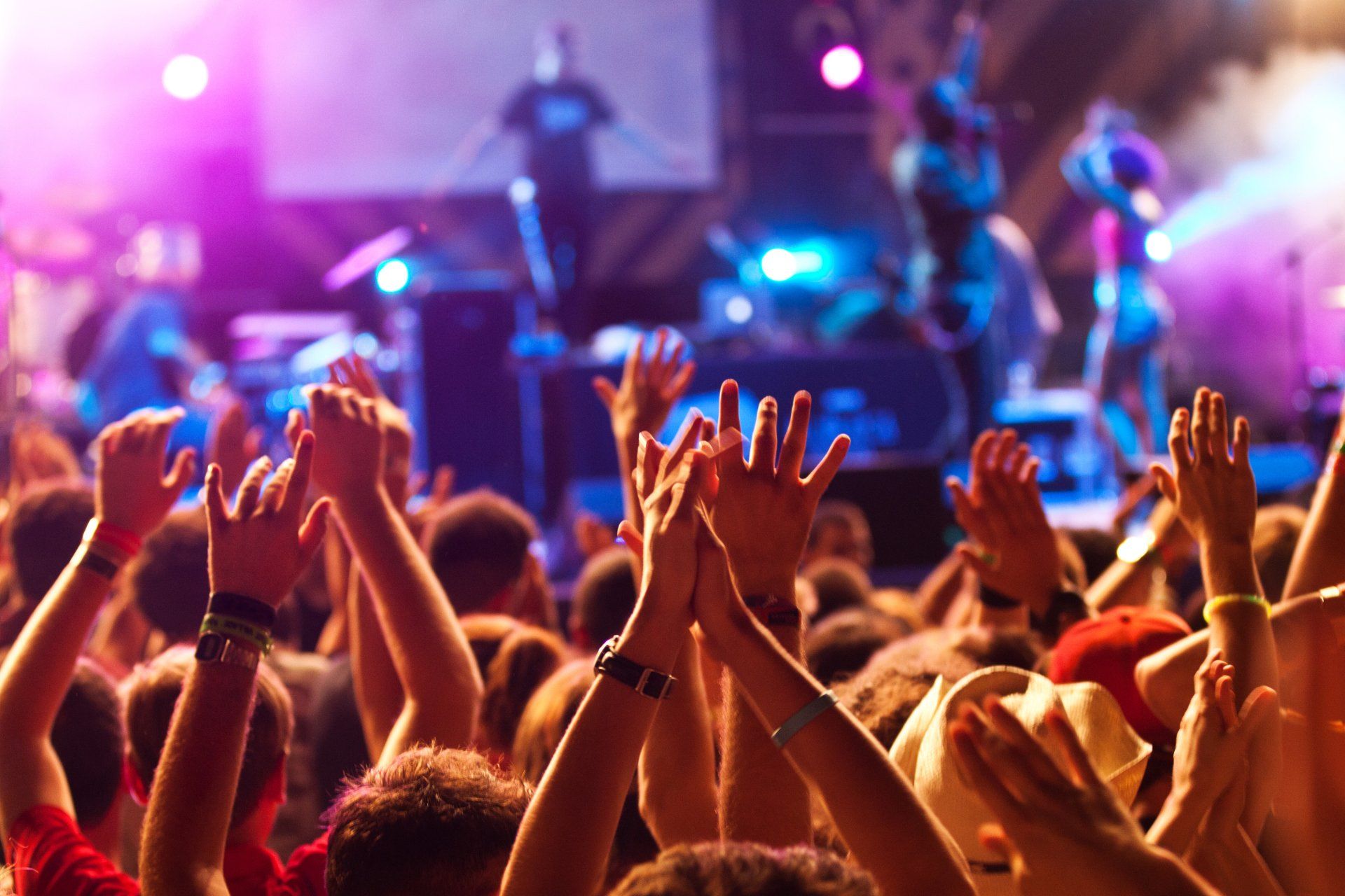 A crowd of people are raising their hands in the air at a concert.