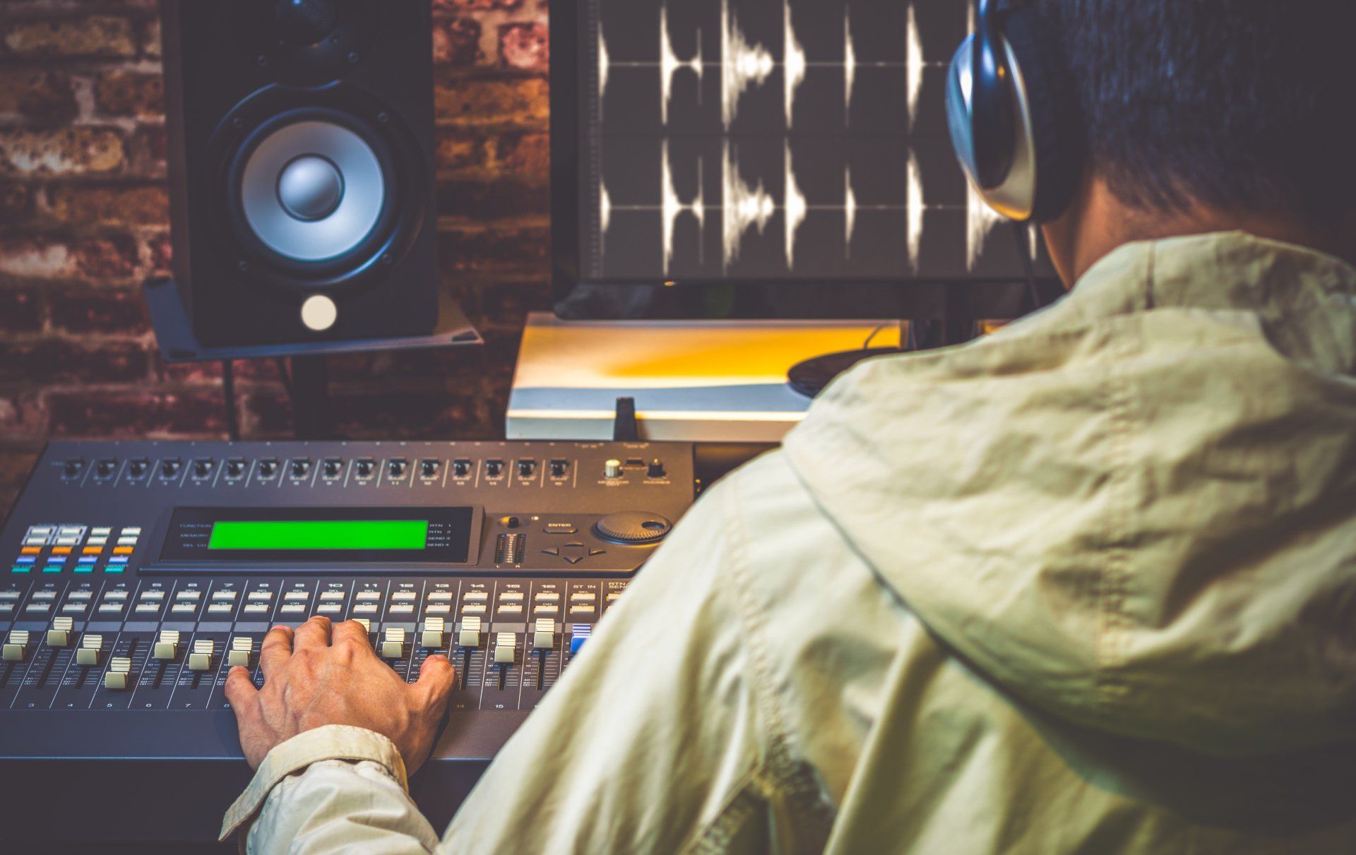A man is using a sound mixer in a recording studio.