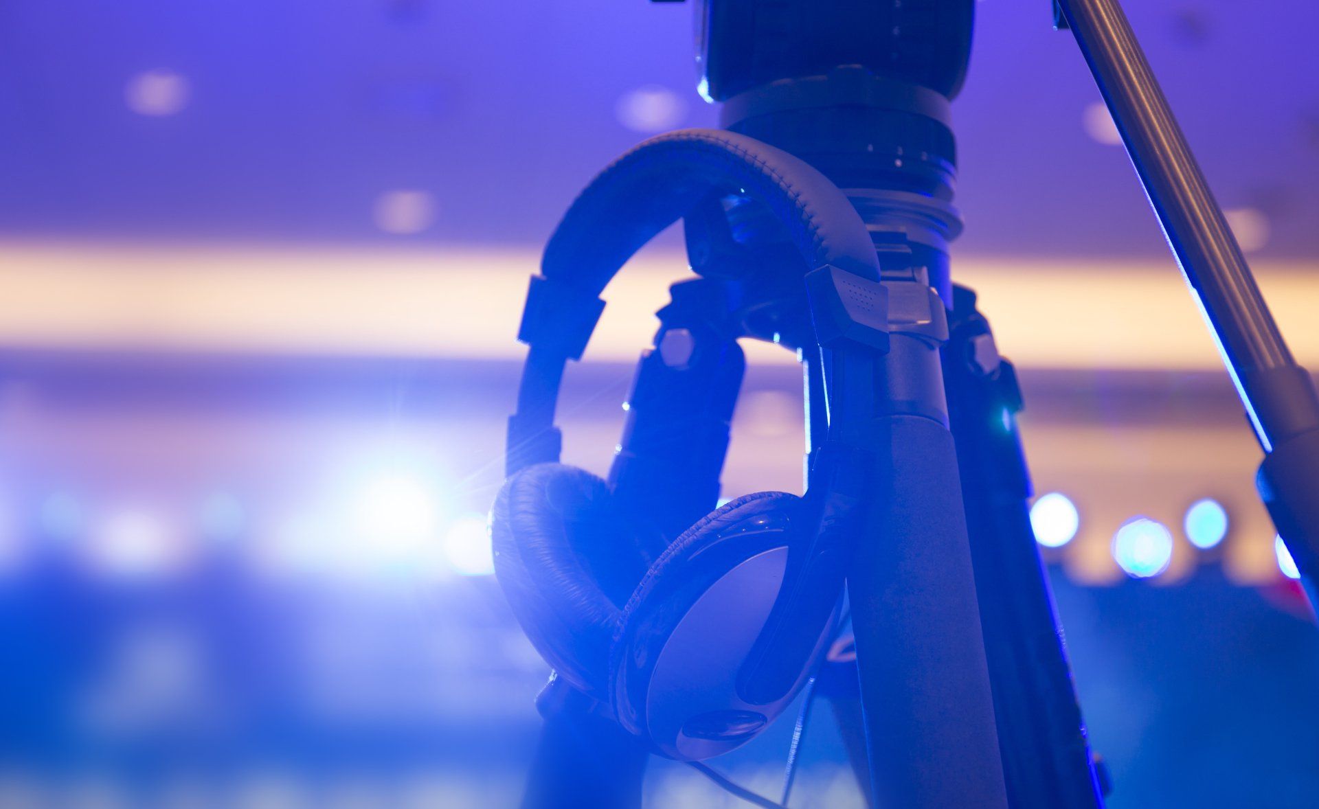 A pair of headphones hanging from a camera on a tripod.