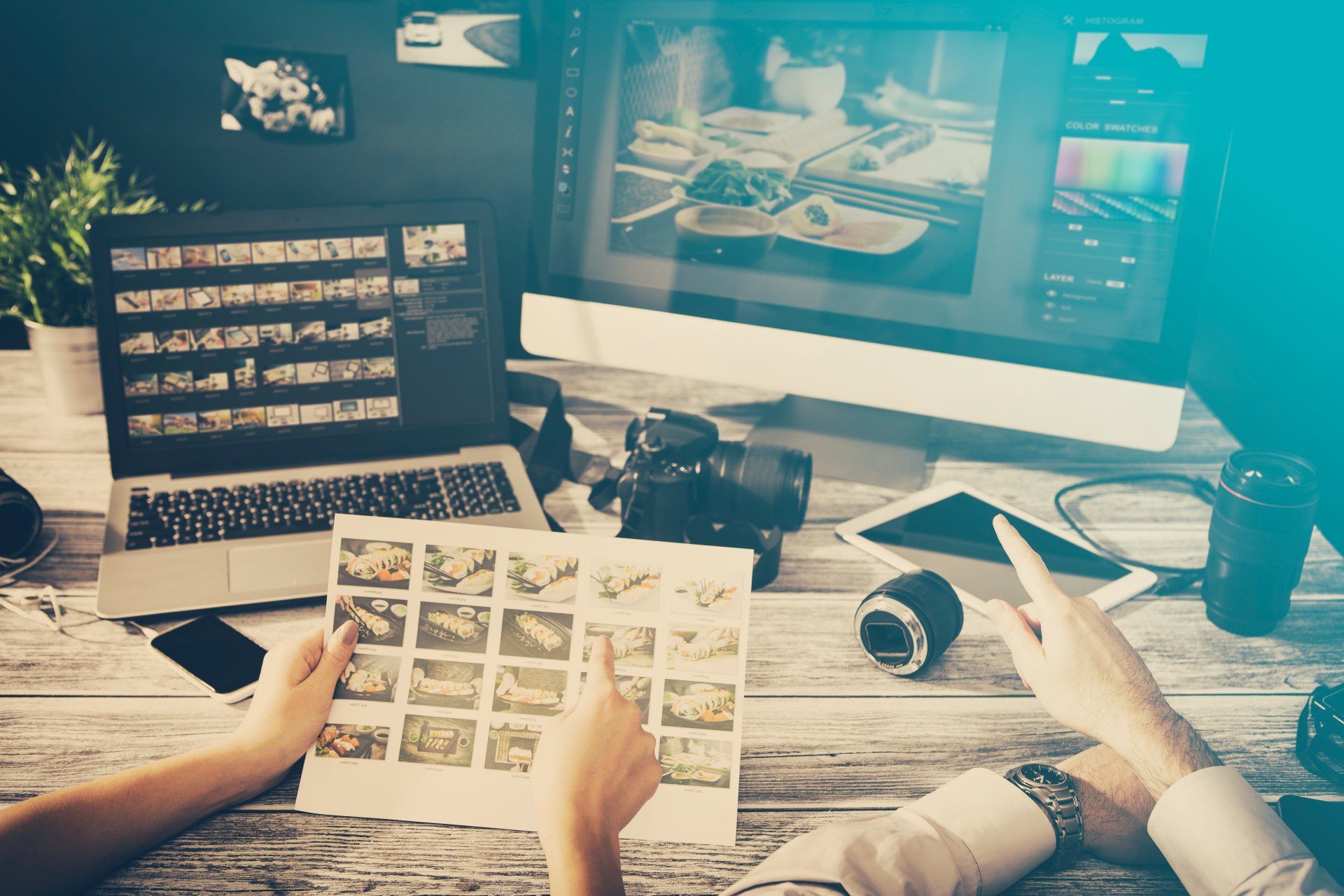 A couple of people are sitting at a table looking at pictures on a laptop.