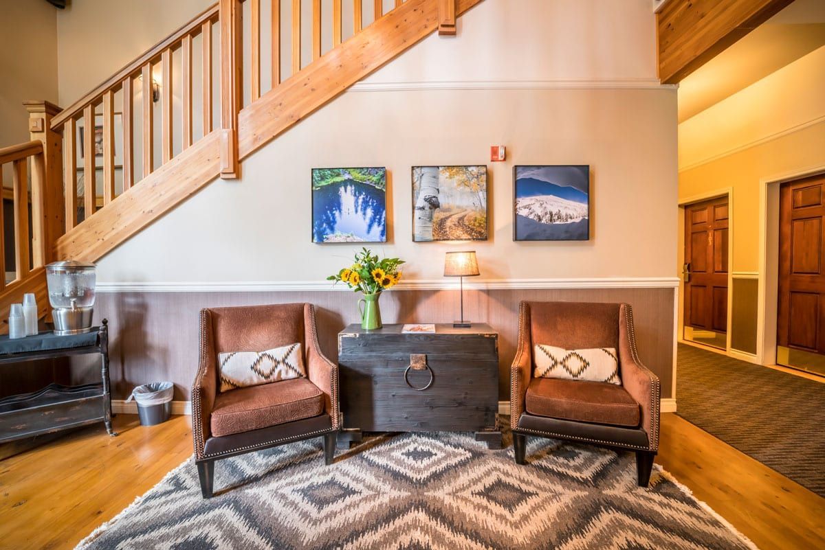 A living room with two chairs , a trunk , and stairs.
