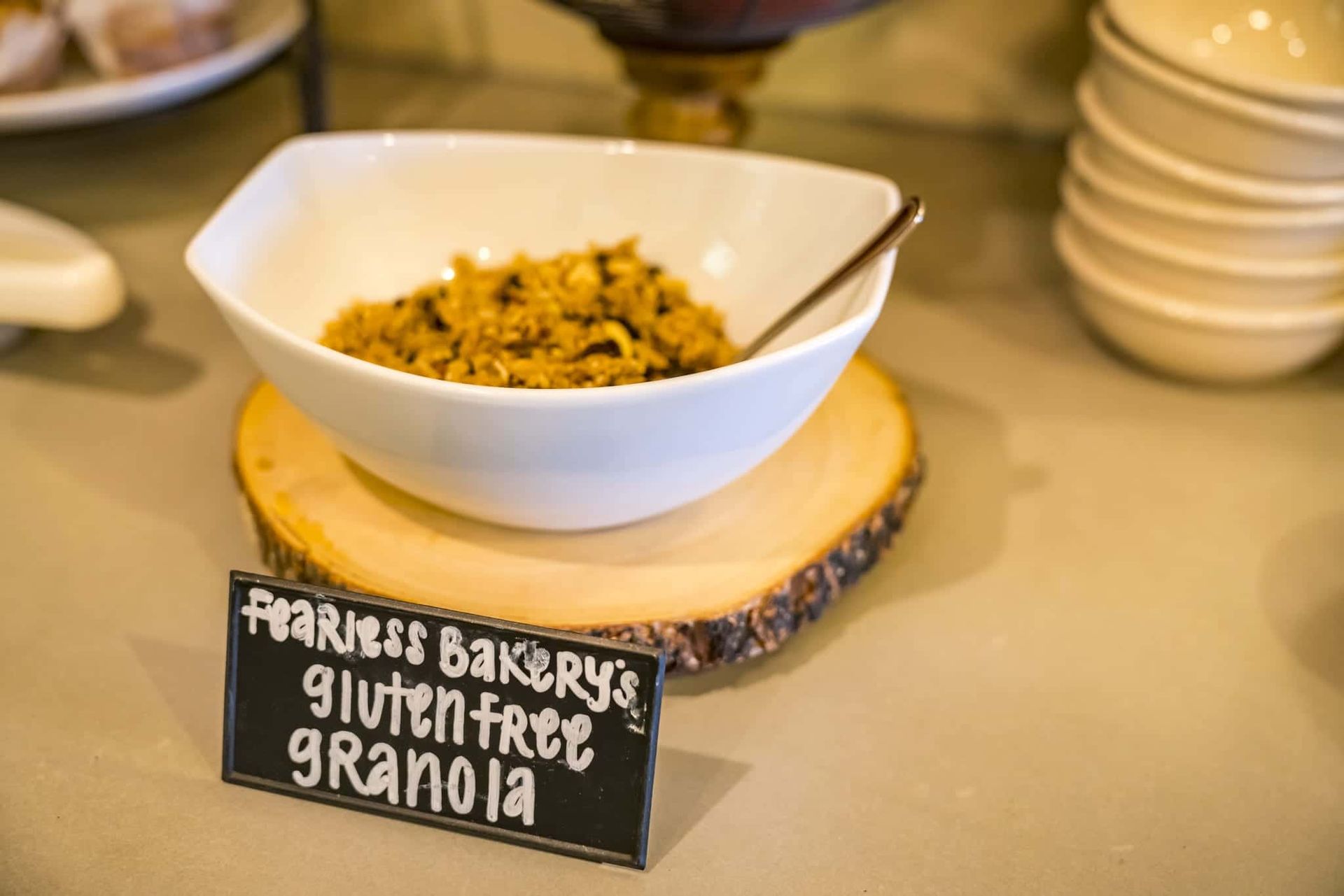 A bowl of gluten free granola is on a wooden cutting board.